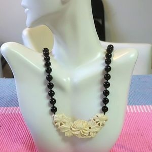 Ivory colored floral carving along black beaded necklace